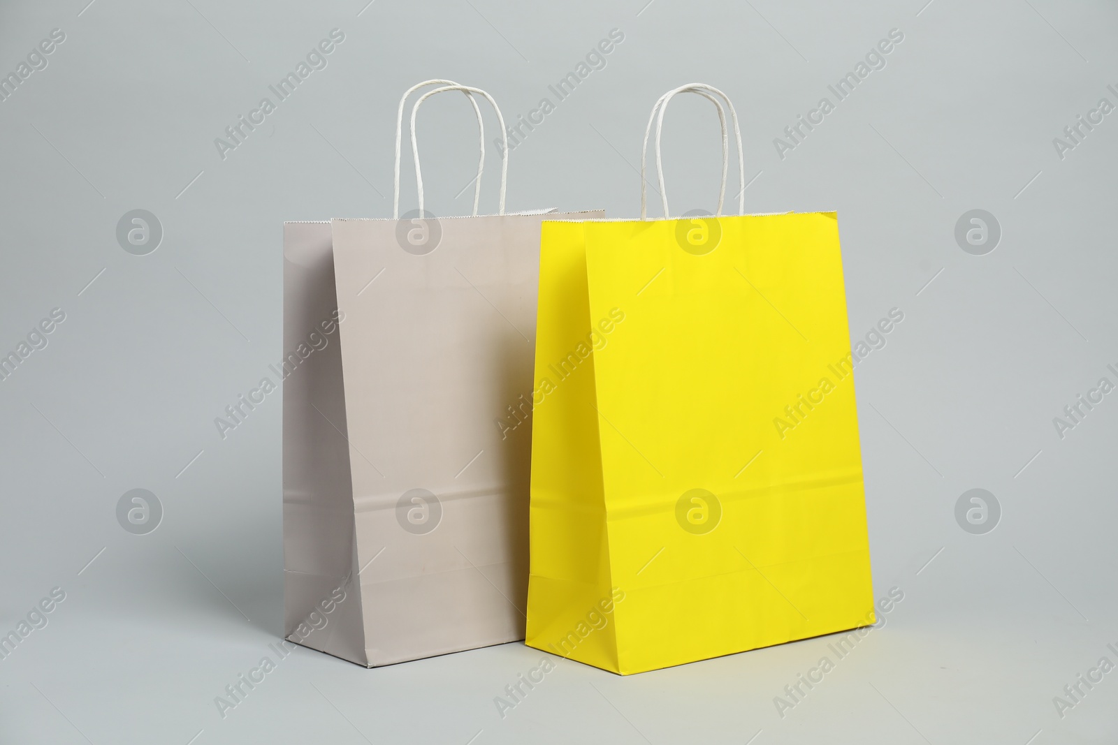 Photo of Two blank shopping bags on light grey background. Mockup for design