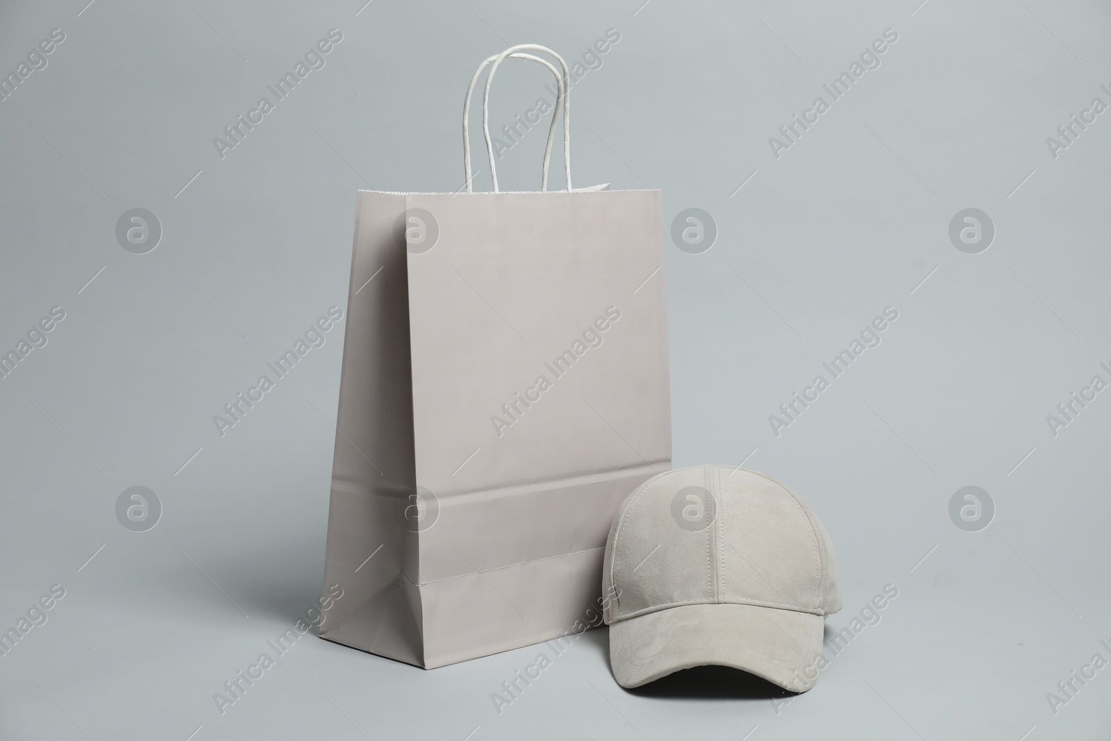 Photo of Blank paper shopping bag and cap for branding on light grey background. Mockup for design