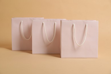 Photo of Blank shopping bags on beige background. Mockup for design