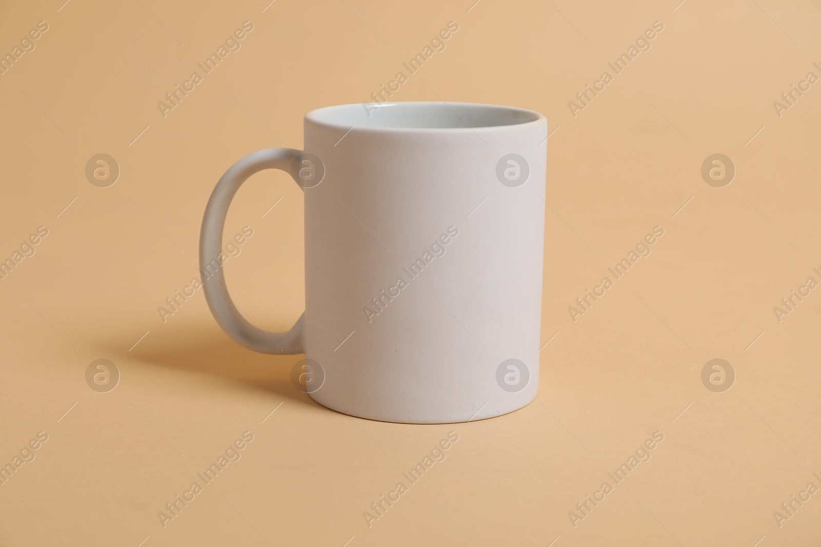 Photo of Blank white mug for branding on beige background. Mockup for design