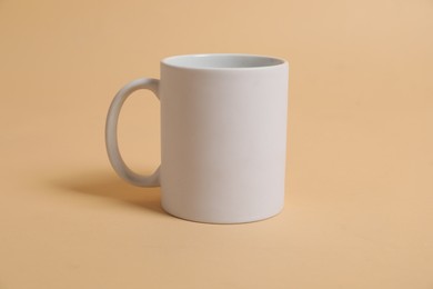 Photo of Blank white mug for branding on beige background. Mockup for design