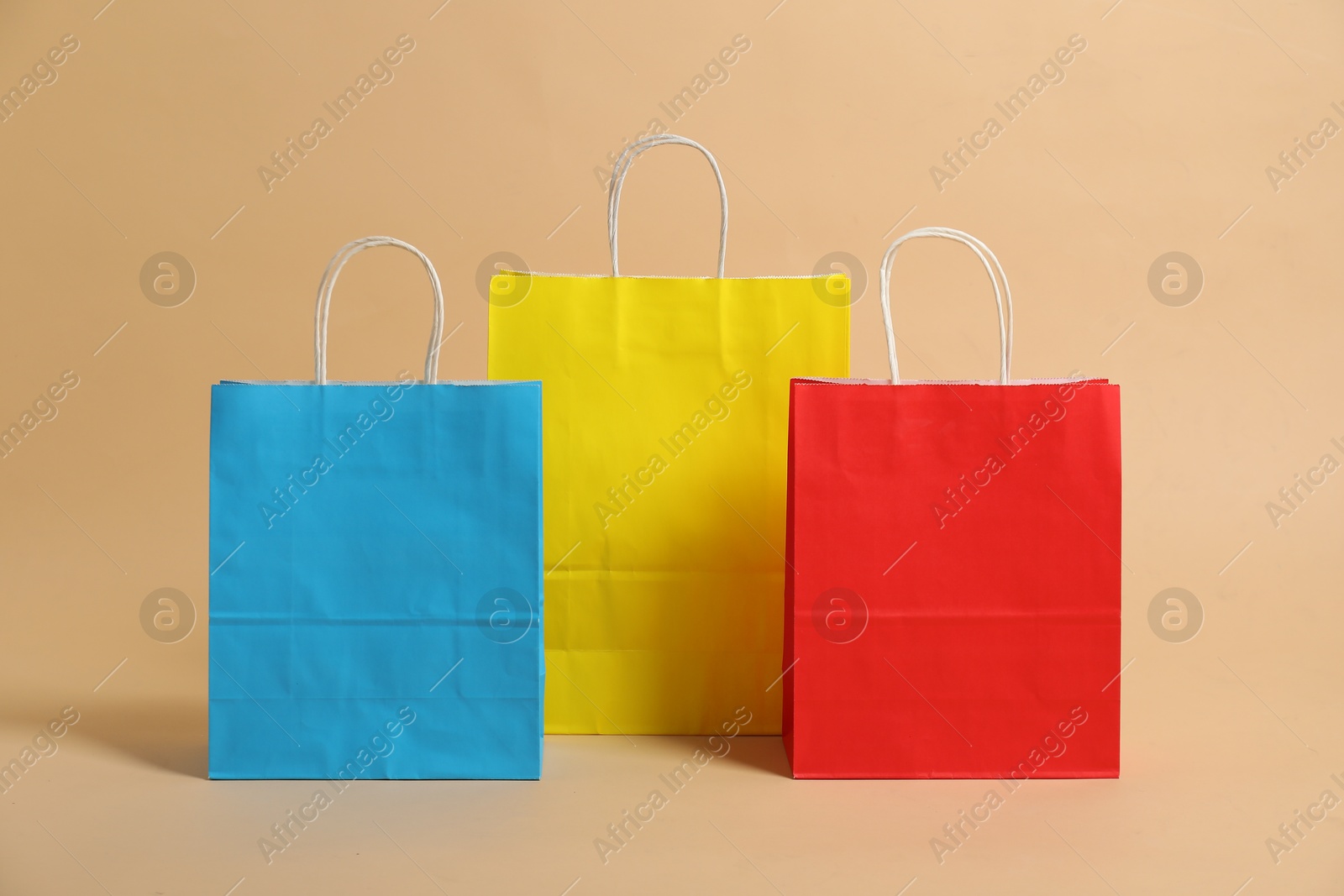 Photo of Blank paper shopping bags on beige background. Mockup for design