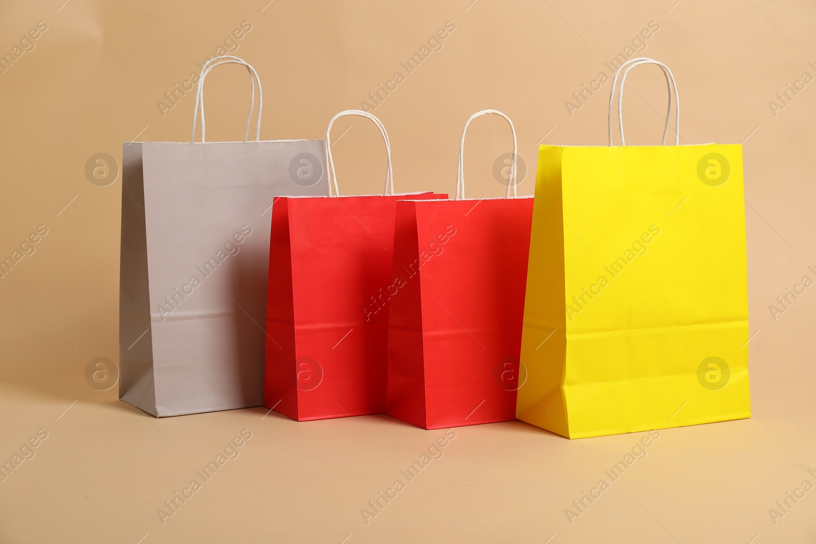 Photo of Blank paper shopping bags on beige background. Mockup for design