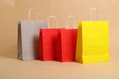 Photo of Blank paper shopping bags on beige background. Mockup for design