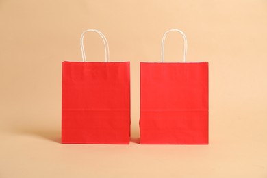 Photo of Two blank red shopping bags on beige background. Mockup for design