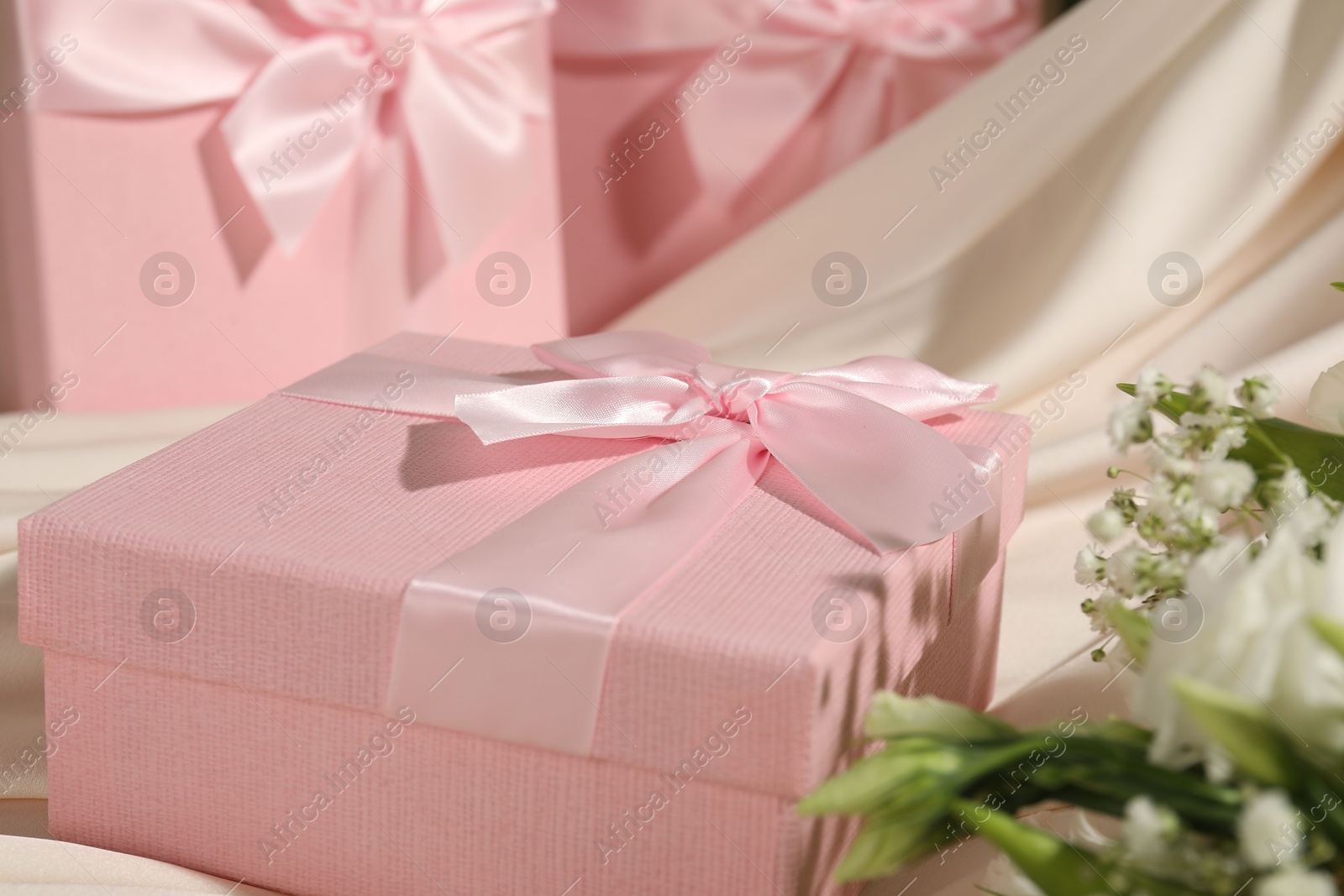 Photo of Beautiful wedding gifts, silk fabric and flowers on table, closeup