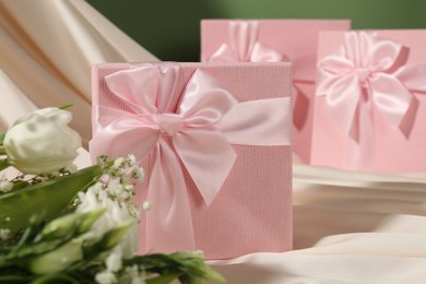 Photo of Beautiful wedding gifts, silk fabric and flowers on table, closeup