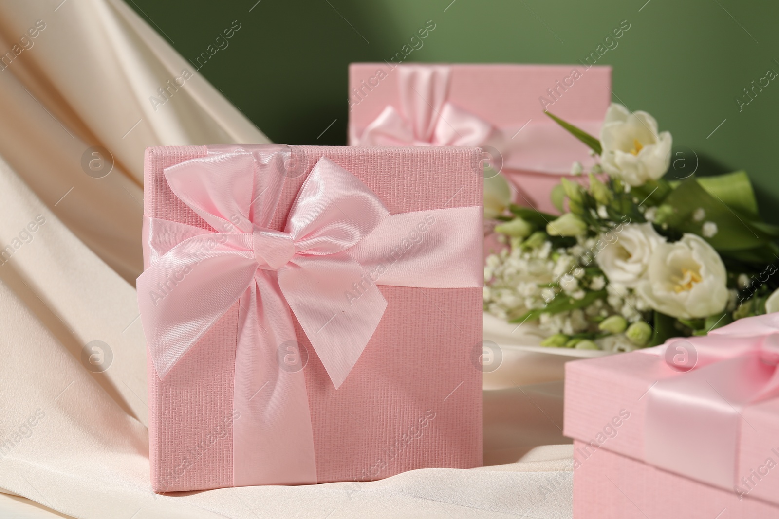 Photo of Beautiful wedding gifts, silk fabric and flowers on table