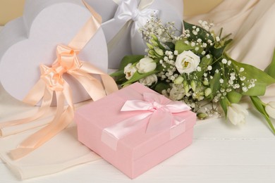 Photo of Beautiful wedding gifts, flowers and silk fabric on white wooden table