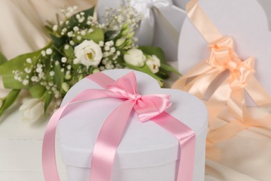 Photo of Beautiful wedding gifts, flowers and silk fabric on table, closeup