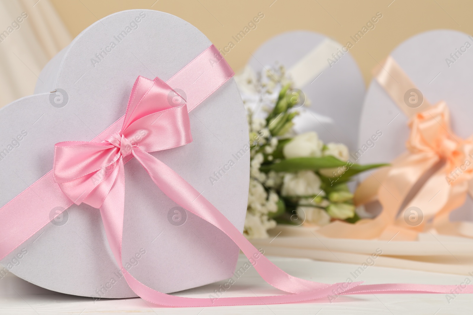 Photo of Beautiful wedding gifts, flowers and silk fabric on white table, closeup