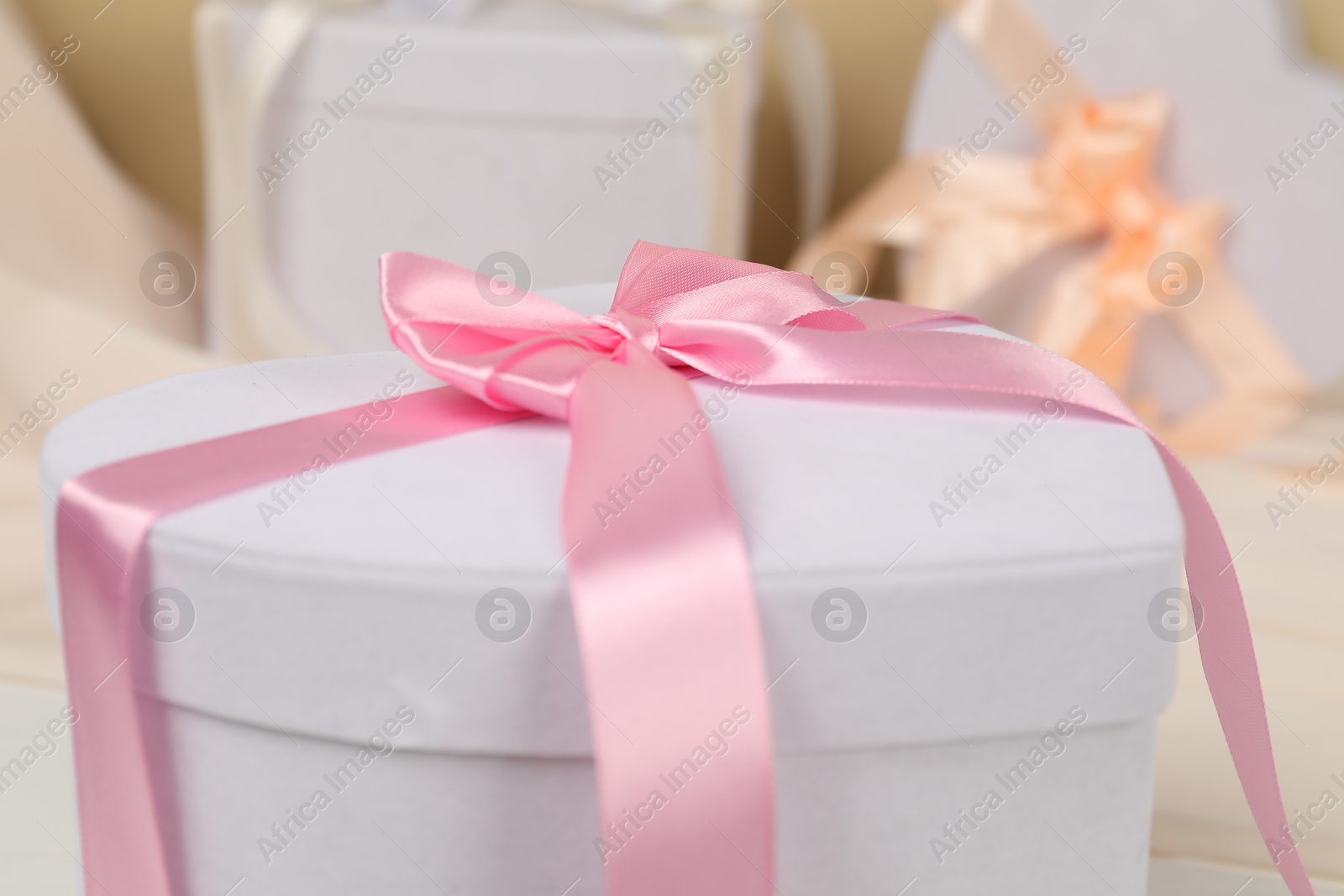 Photo of Beautiful wedding gift with pink bow on blurred background, closeup