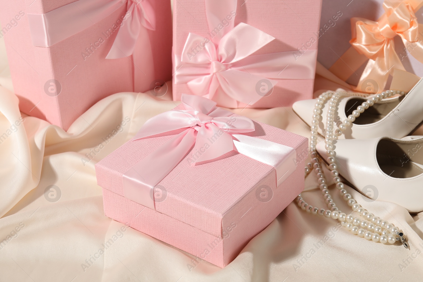 Photo of Beautiful wedding gifts, bridal shoes and pearl jewelry on silk fabric