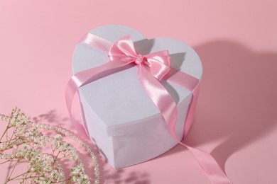 Photo of Beautiful wedding gift, pearl jewelry and gypsophila flowers on pink background, closeup