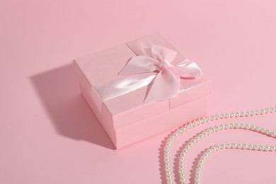 Photo of Beautiful wedding gift and pearl jewelry on pink background