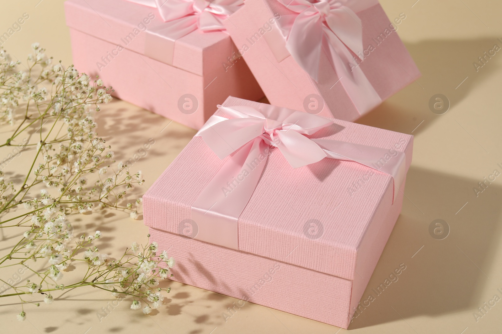 Photo of Beautiful wedding gifts and gypsophila flowers on beige background, closeup