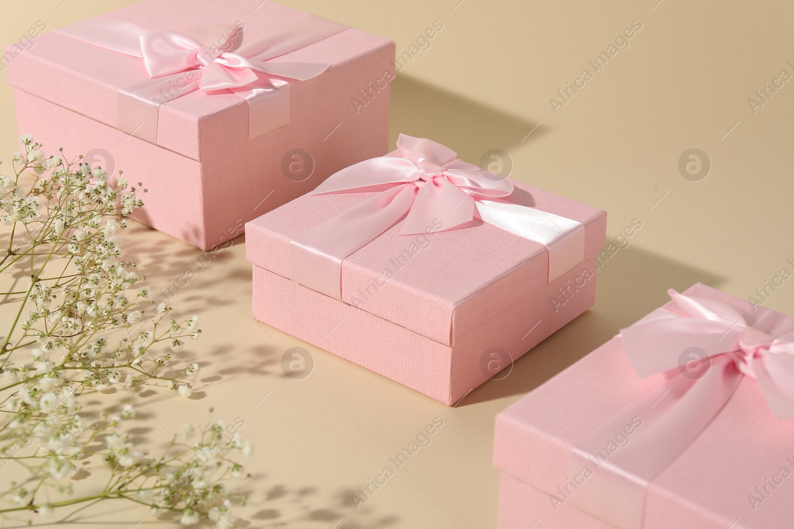 Photo of Beautiful wedding gifts and gypsophila flowers on beige background