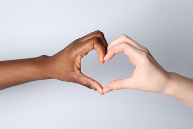 Photo of Stop racism. People of different skin colors making heart with hands on light grey background, closeup