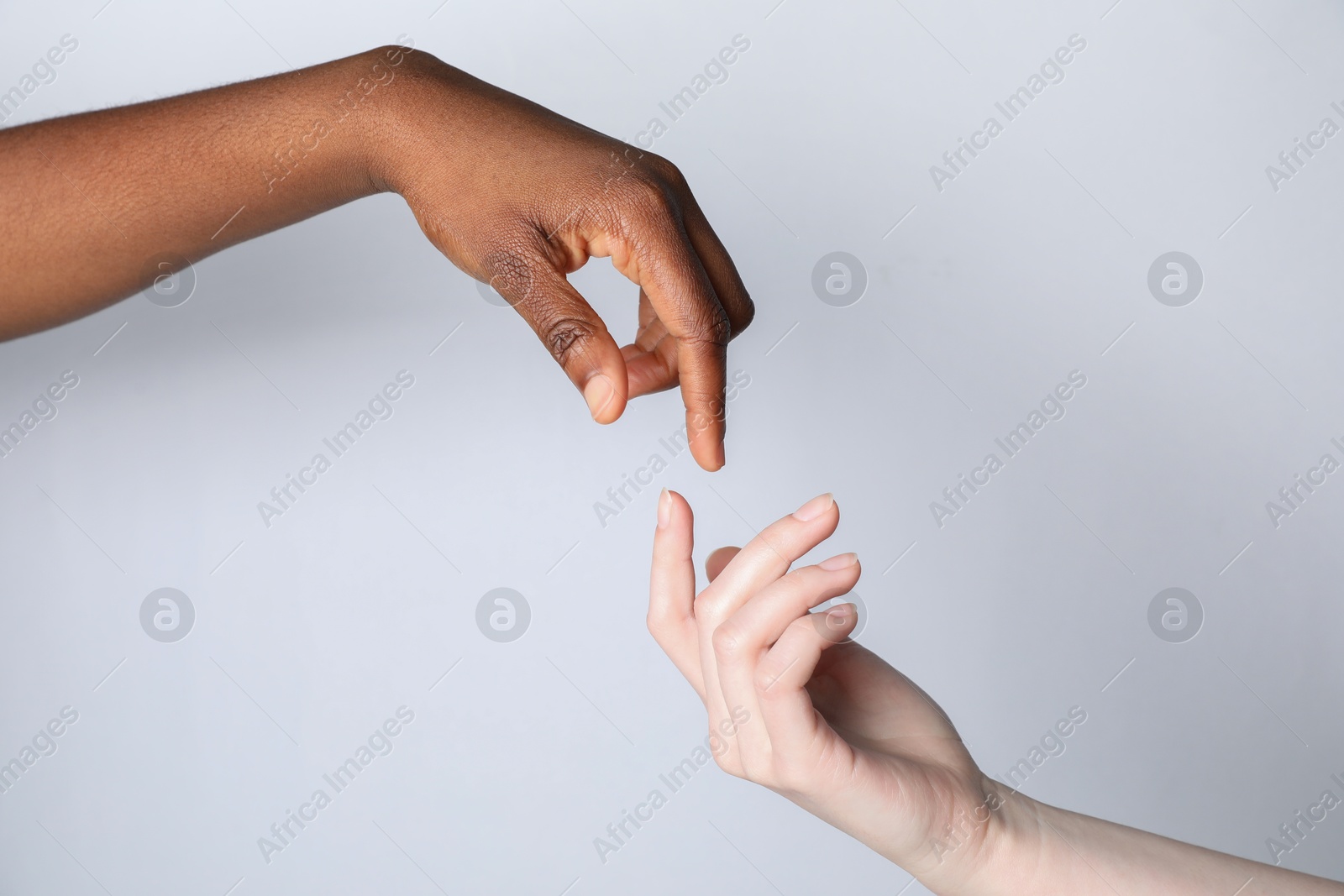 Photo of Stop racism. People of different skin colors joining hands on light grey background, closeup