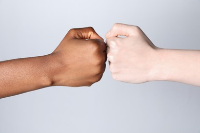 Photo of Stop racism. People of different skin colors bumping fists on light grey background, closeup