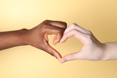 Photo of Stop racism. People of different skin colors making heart with hands on beige background, closeup