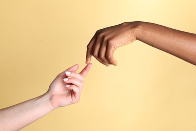 Photo of Stop racism. People of different skin colors joining hands on beige background, closeup