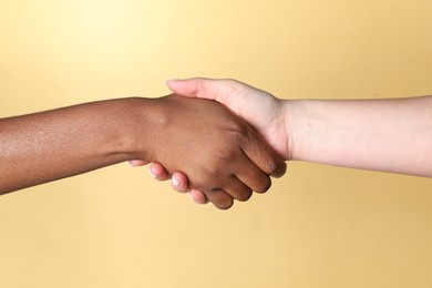 Photo of Stop racism. People of different skin colors shaking hands on beige background, closeup