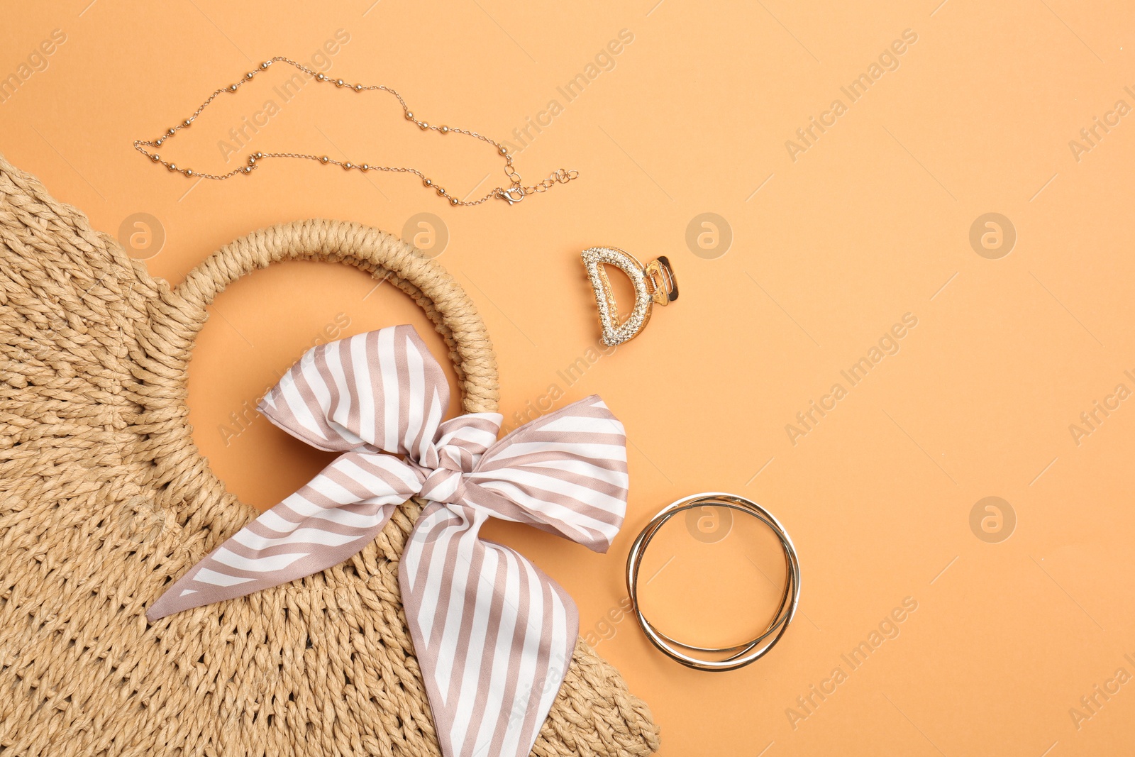 Photo of Beautiful bag and stylish accessories on pale orange background, flat lay. Space for text