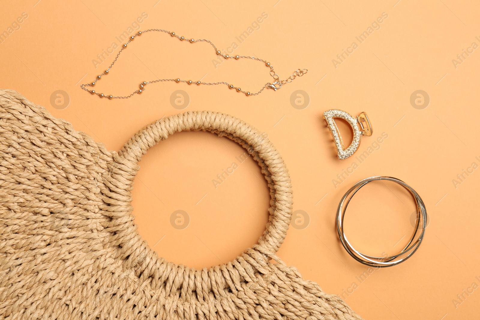 Photo of Beautiful bag and stylish accessories on pale orange background, flat lay