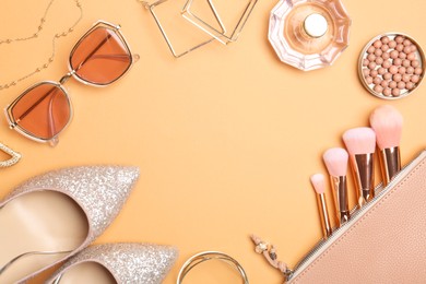 Photo of Frame of shoes and stylish accessories on pale orange background, flat lay. Space for text