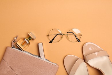 Photo of Beautiful bag, shoes and stylish accessories on pale orange background, flat lay