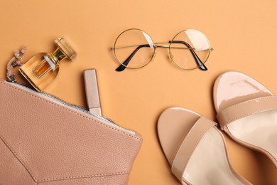 Photo of Beautiful bag, shoes and stylish accessories on pale orange background, flat lay