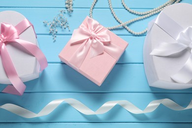 Photo of Beautiful wedding gifts, ribbon and pearl jewelry on light blue wooden table, flat lay