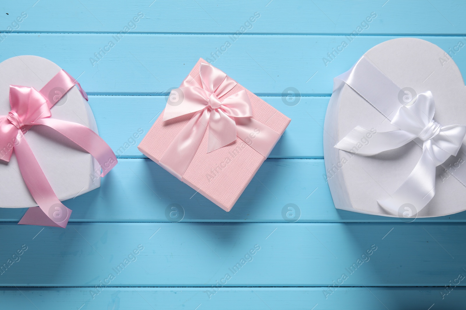 Photo of Beautiful wedding gifts on light blue wooden table, flat lay