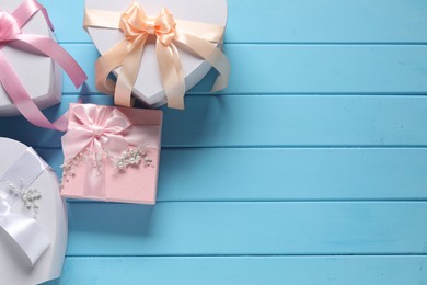 Photo of Beautiful wedding gifts and pearl jewelry on light blue wooden table, flat lay. Space for text