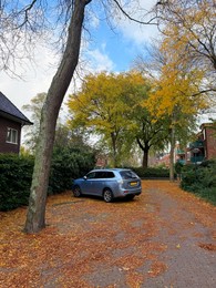 Photo of Parked car and fallen leaves in residential area on autumn day