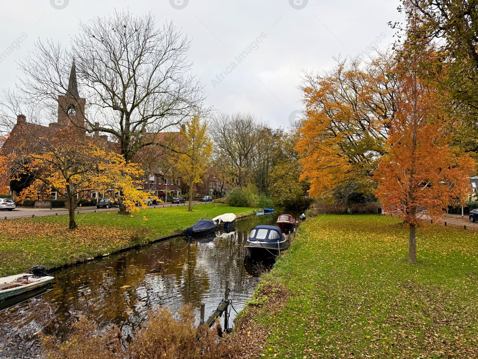 Photo of Beautiful view of canal with moored boats and colorful fallen leaves on autumn day