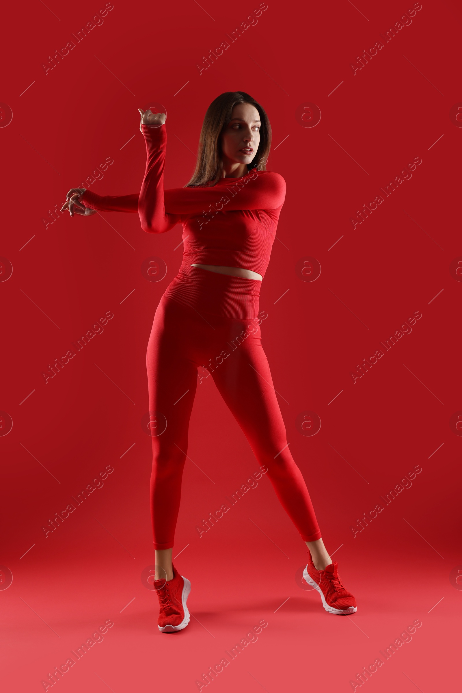 Photo of Beautiful woman in stylish sportswear on red background