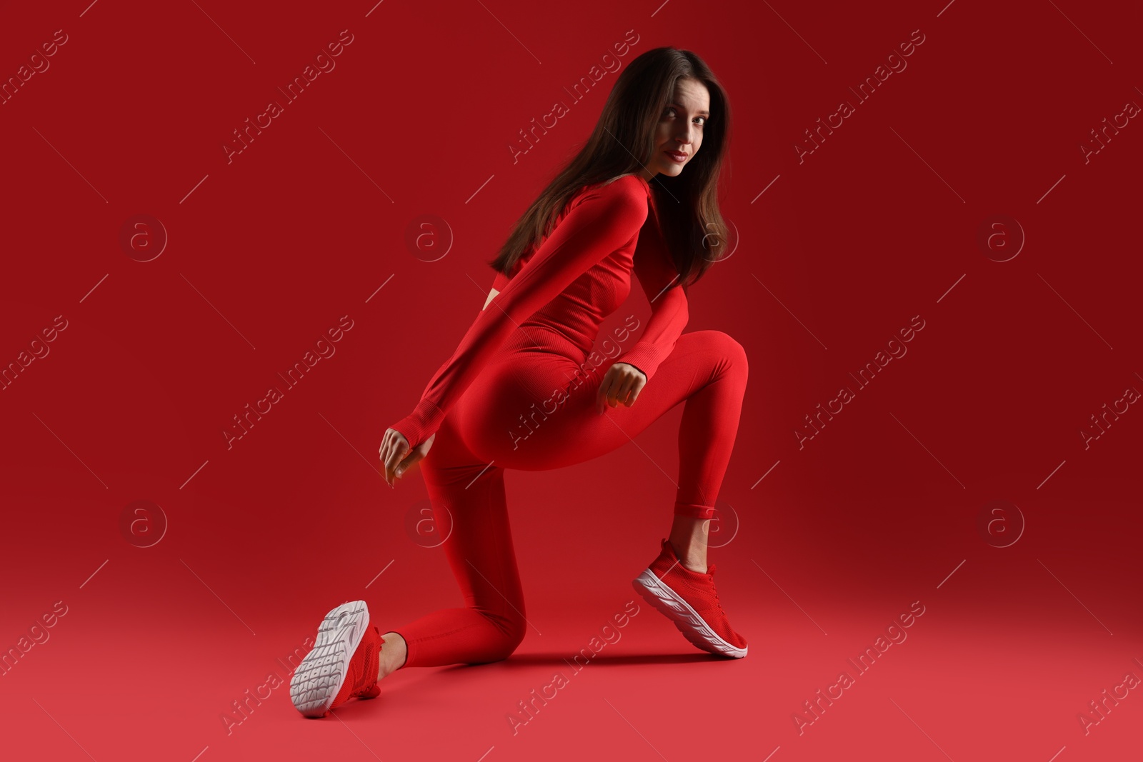 Photo of Beautiful woman in stylish sportswear on red background