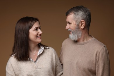 Photo of Happy daughter and her father looking at each other on brown background