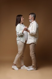 Photo of Happy daughter dancing with her father on brown background