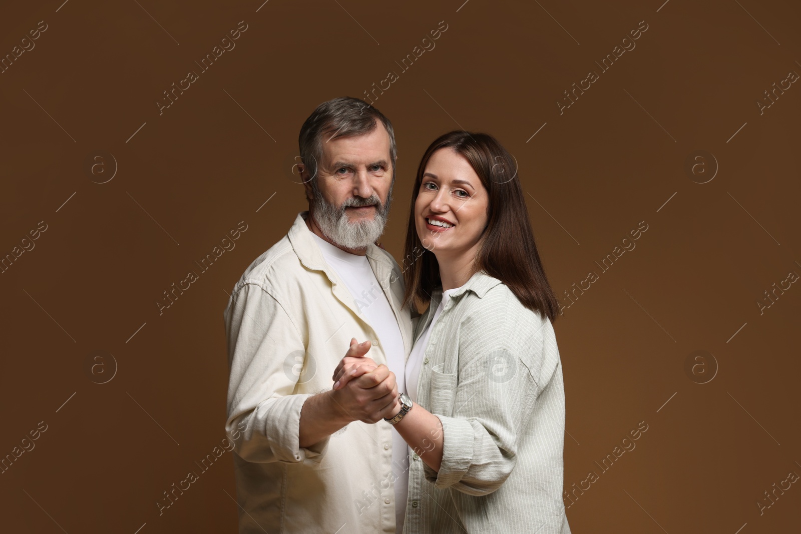 Photo of Happy daughter dancing with her father on brown background