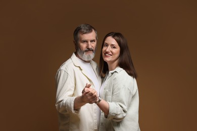 Photo of Happy daughter dancing with her father on brown background