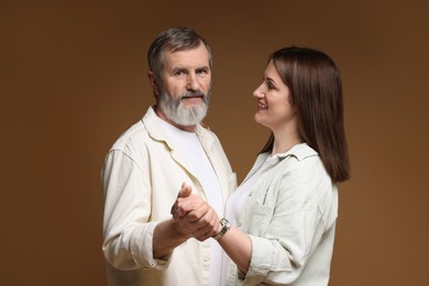 Photo of Happy daughter dancing with her father on brown background