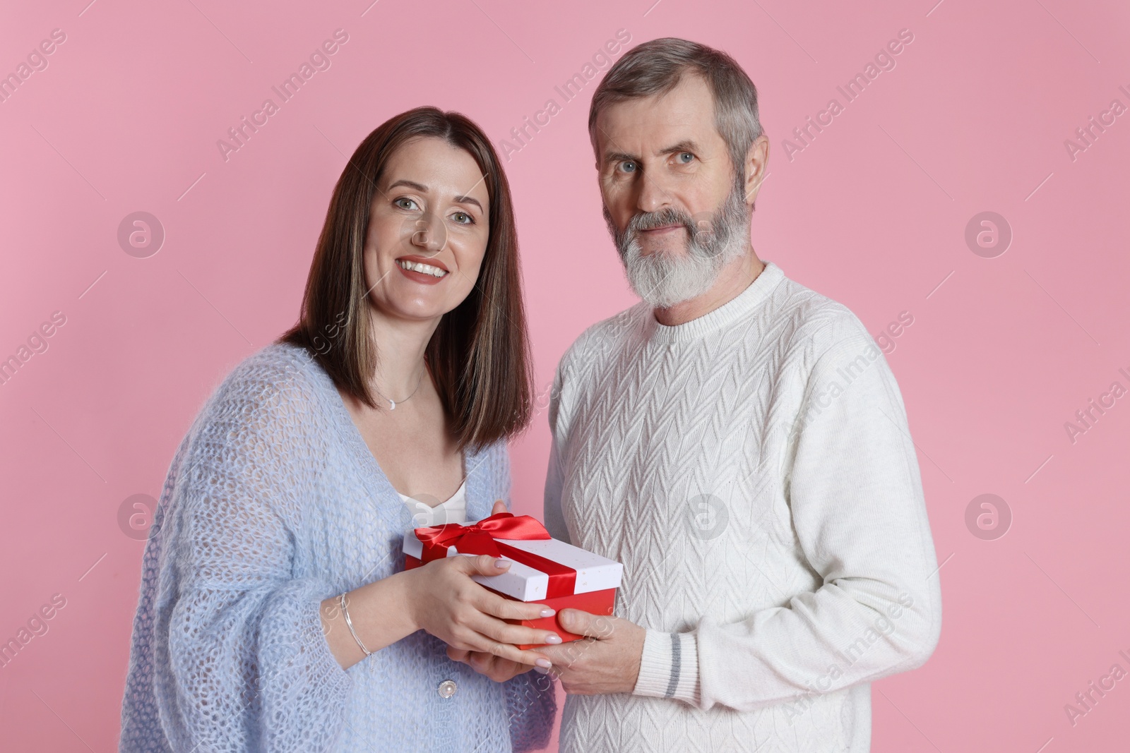 Photo of Family portrait of happy daughter and her father with gift on pink background