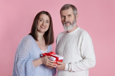 Photo of Family portrait of happy daughter and her father with gift on pink background