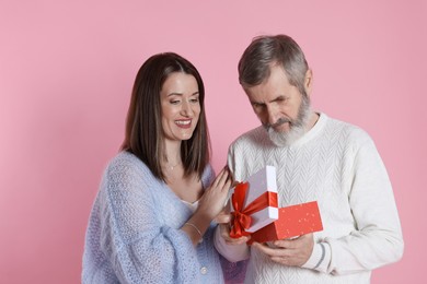 Photo of Father receiving gift from his daughter on pink background