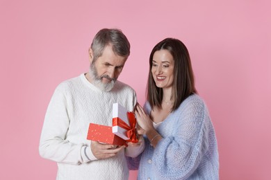 Photo of Father receiving gift from his daughter on pink background