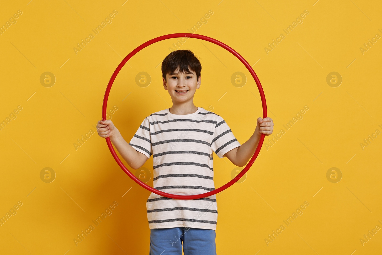 Photo of Smiling boy with hula hoop on yellow background