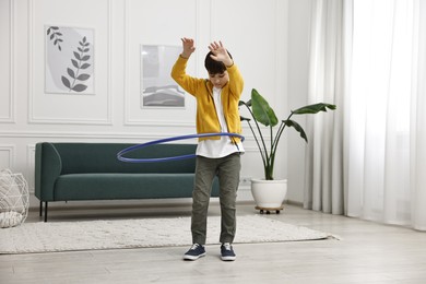 Photo of Boy exercising with hula hoop at home